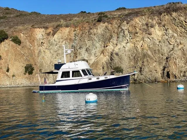 Slide: The Image of 2001 Northern Bay 36 boat anchored near rocky cliffs with buoys in calm water. - 3