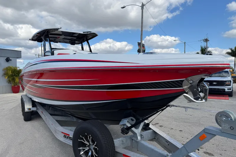 Slide: The Image of 2025 Sunsation 32 CCX boat in vibrant red on a trailer, under a partly cloudy sky. - 5