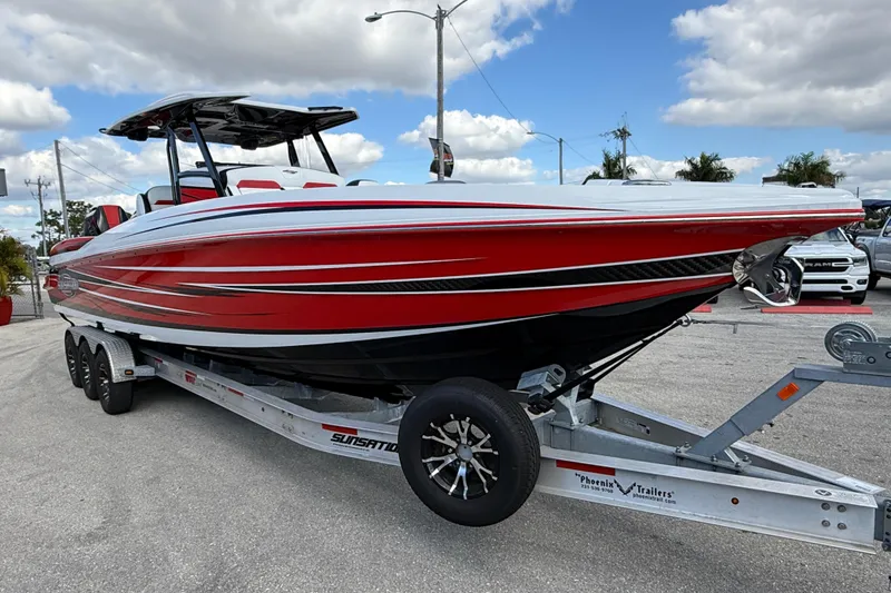 Slide: The Image of 2025 Sunsation 32 CCX boat in red on a trailer, parked outdoors under a cloudy sky. - 6