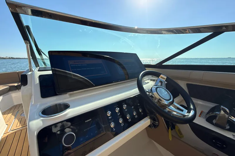 Slide: The Image of 2021 Sea Ray SLX 310 Outboard helm with steering wheel and control panel, overlooking the ocean. - 13
