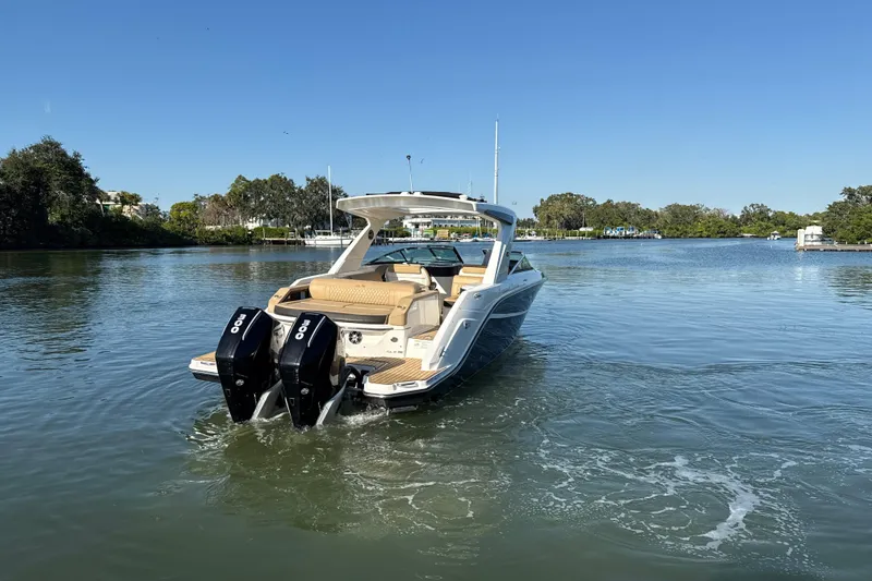 Slide: The Image of 2021 Sea Ray SLX 310 Outboard cruising on a serene lake under clear blue skies. - 24