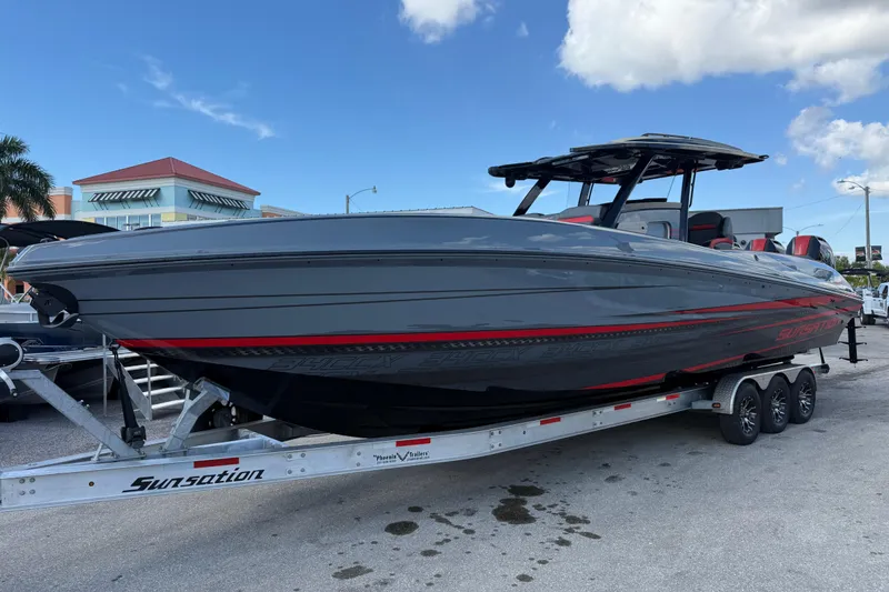 The Image of 2026 Sunsation 34 CCX powerboat on trailer, sleek gray design with red accents. - 1