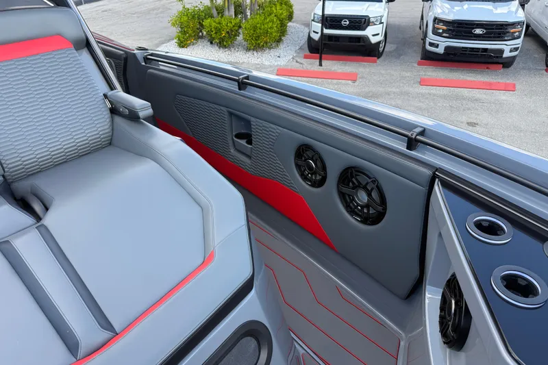 Slide: The Image of 2026 Sunsation 34 CCX boat interior with gray and red seating, cup holders, and speakers. - 19