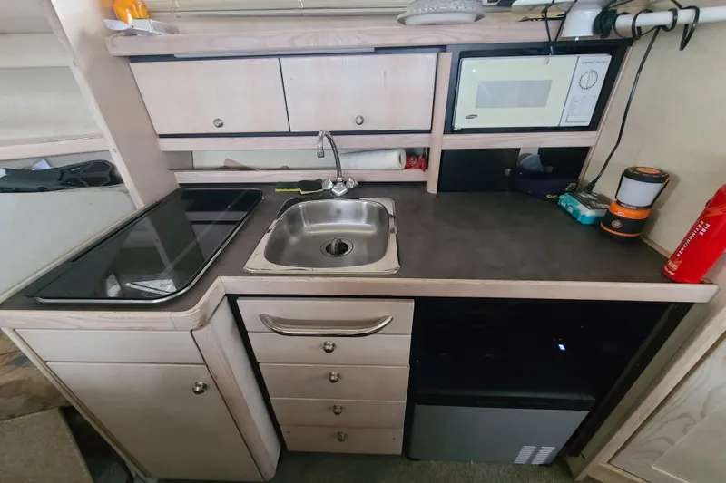 Slide: The Image of 1997 Bayliner 3255 Avanti kitchen with sink, stove, microwave, and storage cabinets. - 13