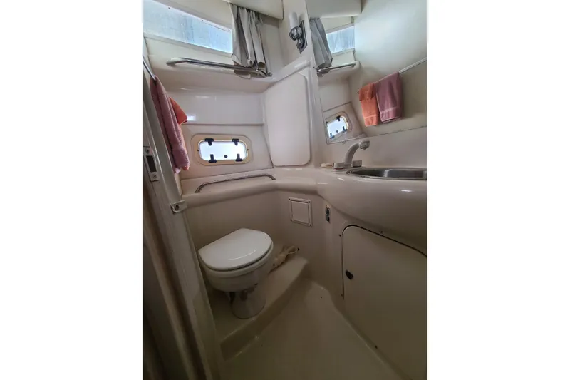 Slide: The Image of 1997 Bayliner 3255 Avanti boat bathroom with toilet, sink, and porthole windows. - 15