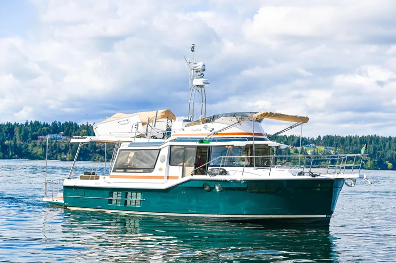 The Image of 2022 Ranger Tugs R-43 CB boat on a serene lake with forested background. - 0
