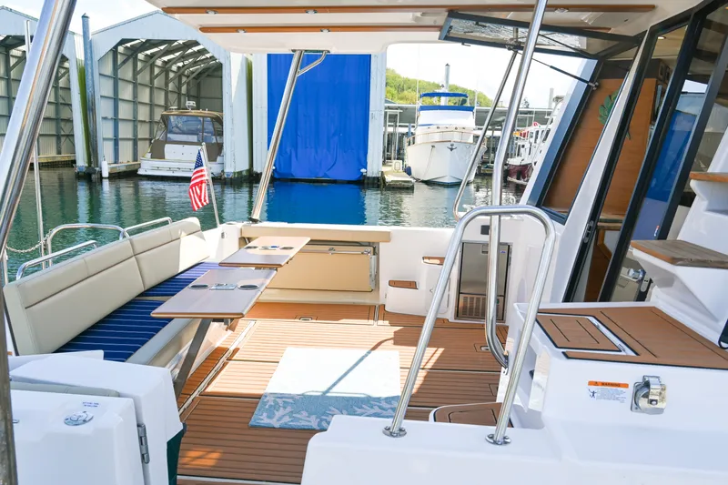 Slide: The Image of 2022 Ranger Tugs R-43 CB yacht interior with seating, table, and American flag at marina. - 16