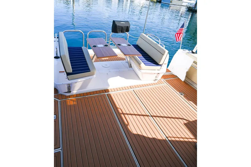 Slide: The Image of 2022 Ranger Tugs R-43 CB boat deck with seating and tables, docked by calm water. - 17