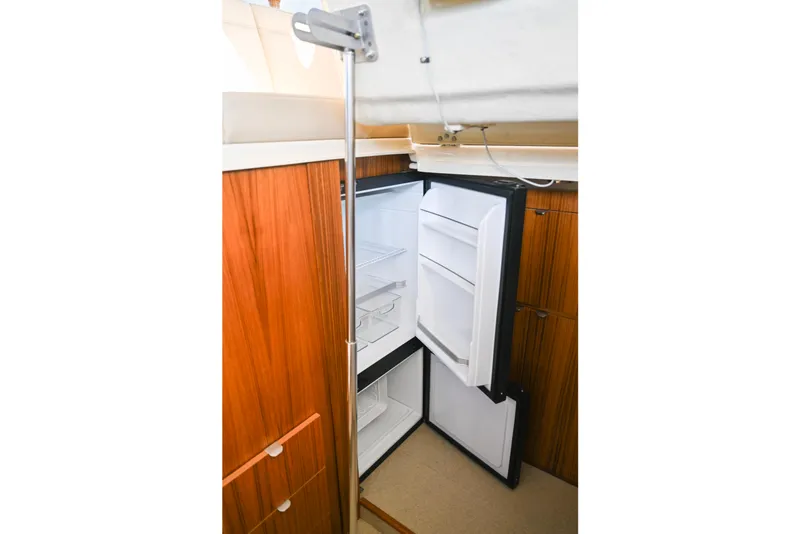 Slide: The Image of 2022 Ranger Tugs R-43 CB interior with open refrigerator and wooden cabinetry. - 34