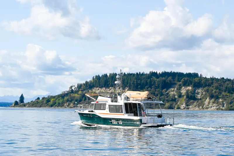 Slide: The Image of 2022 Ranger Tugs R-43 CB cruising on a scenic lake with forested hills. - 5