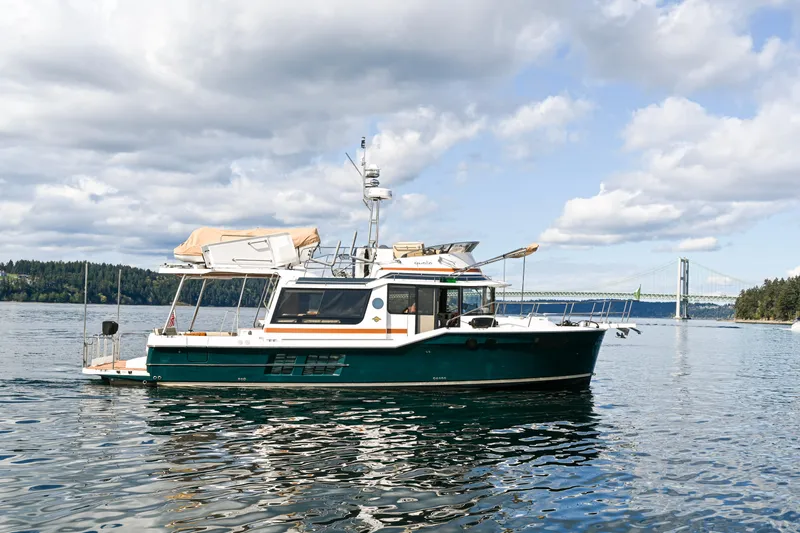 Slide: The Image of 2022 Ranger Tugs R-43 CB boat on calm water with bridge in background. - 6