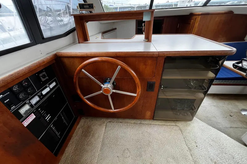 Slide: The Image of 1991 Carver 33 Aft Cabin Motor Yacht helm with wooden steering wheel and control panel. - 27
