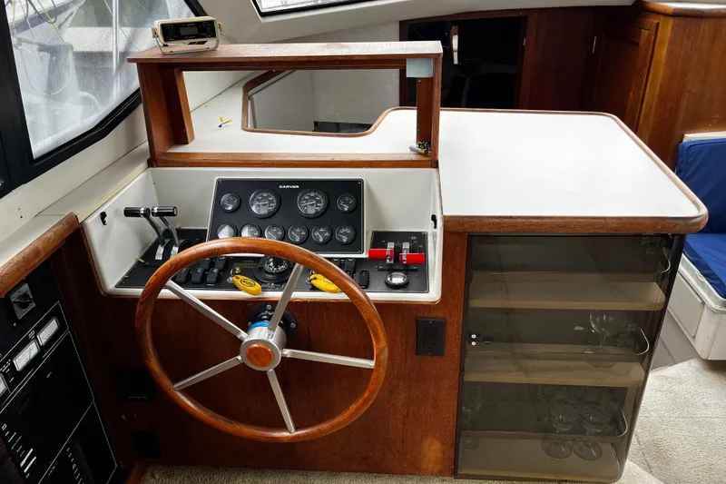 Slide: The Image of 1991 Carver 33 Aft Cabin Motor Yacht helm with wooden steering wheel and control panel. - 28