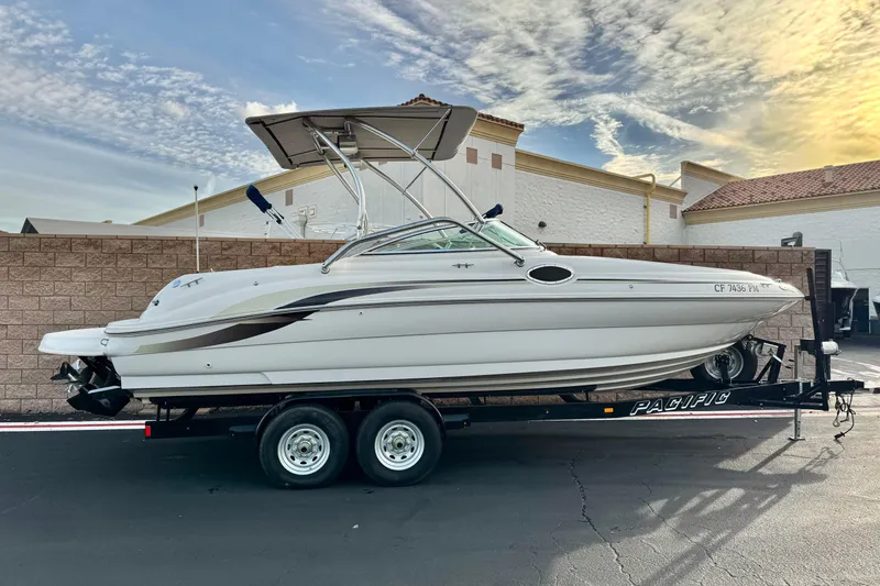 The Image of 2001 Sea Ray 240 Sundeck boat on trailer, parked outdoors under a cloudy sky. - 0