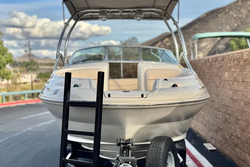 Slide: The Image of 2001 Sea Ray 240 Sundeck boat on trailer, parked outdoors with scenic background. - 2