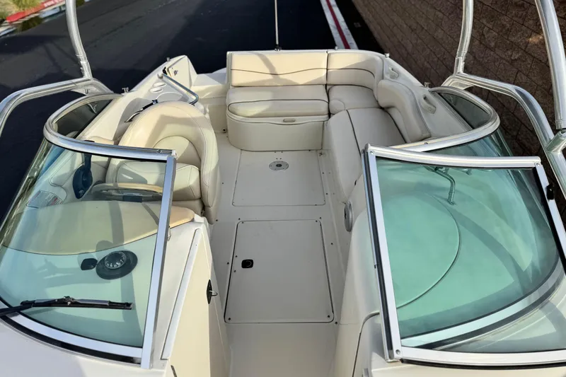 Slide: The Image of 2001 Sea Ray 240 Sundeck interior with beige seating and dual windshields. - 21