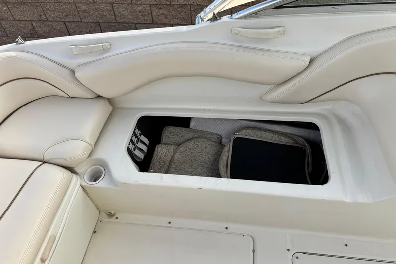 Slide: The Image of 2001 Sea Ray 240 Sundeck interior storage compartment with white cushioned seating. - 28