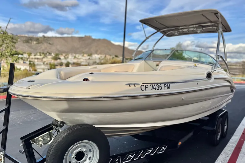 Slide: The Image of 2001 Sea Ray 240 Sundeck boat on trailer, parked outdoors under a cloudy sky. - 3