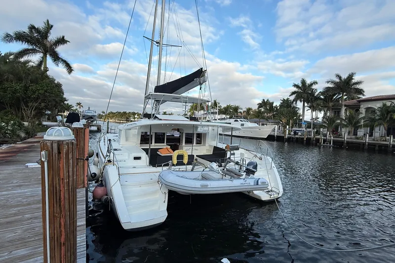 Slide: The Image of 2019 Lagoon 450 catamaran docked by palm trees under a partly cloudy sky. - 4