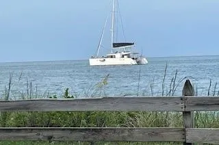 Slide: The Image of 2019 Lagoon 450 catamaran sailing on calm sea, viewed from behind a wooden fence. - 48