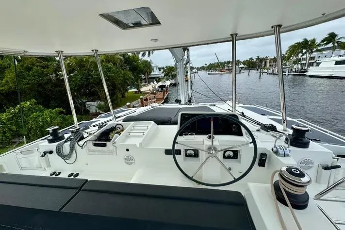 Slide: The Image of Cockpit view of 2019 Lagoon 450 catamaran, featuring steering wheel and marina backdrop. - 9