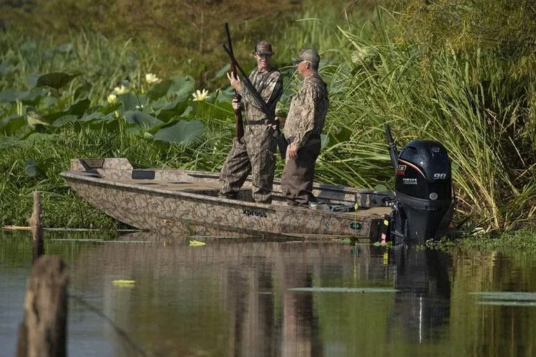 Slide: The Image of Manufacturer Provided Image: Two hunters on a 2026 Xpress X18DB boat in a lush, marshy area. - 27