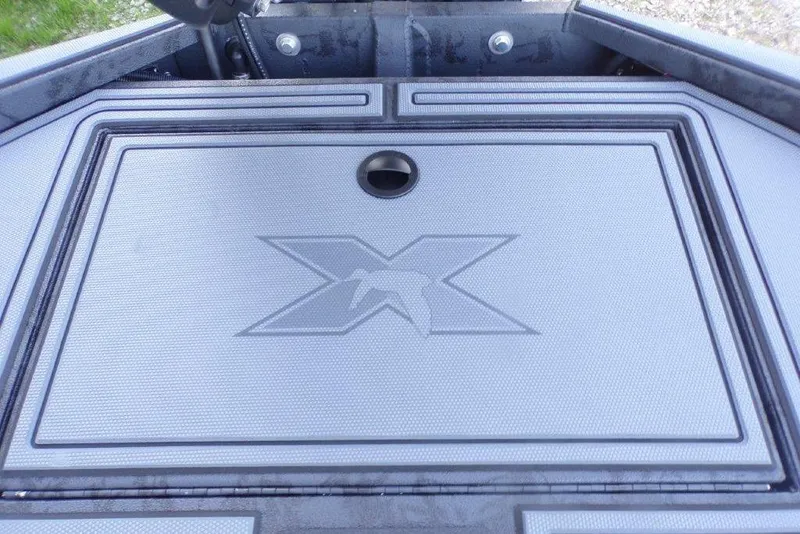 Slide: The Image of 2026 Xpress X18DB boat deck with logo, featuring textured surface and storage compartment. - 8
