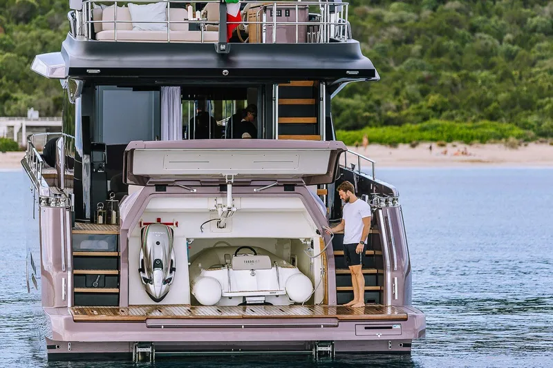 Slide: The Image of 2026 Cranchi Sessantadue 62 yacht with open garage and man on deck. - 44