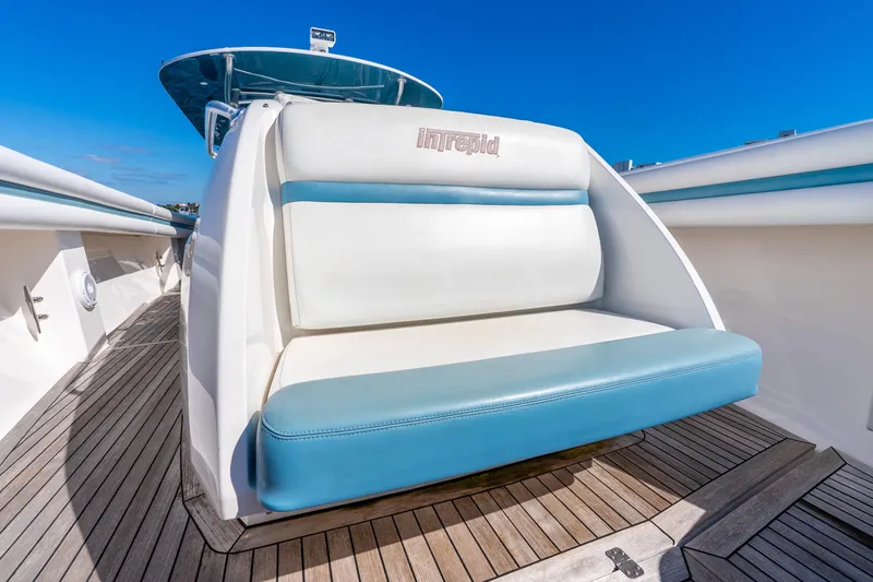 Slide: The Image of 2015 Intrepid 475 Panacea boat seat with blue and white upholstery on teak deck. - 14