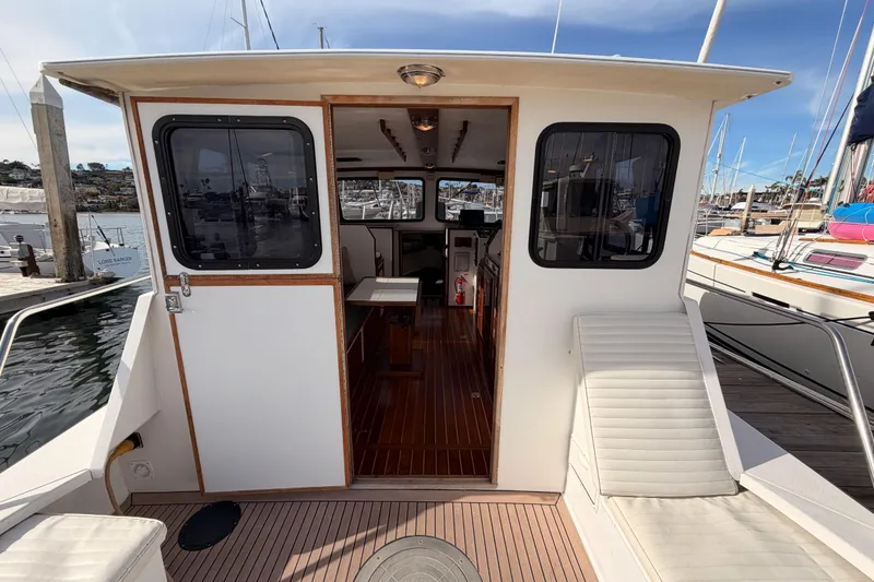Slide: The Image of 2002 Eastern Downeast 35 boat interior with wooden flooring and seating at a marina. - 13