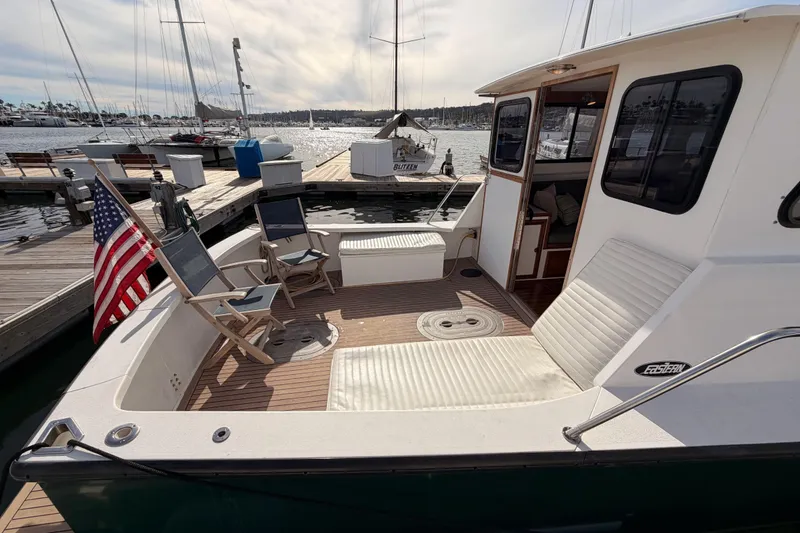 Slide: The Image of 2002 Eastern Downeast 35 boat with deck chairs and American flag at marina. - 7