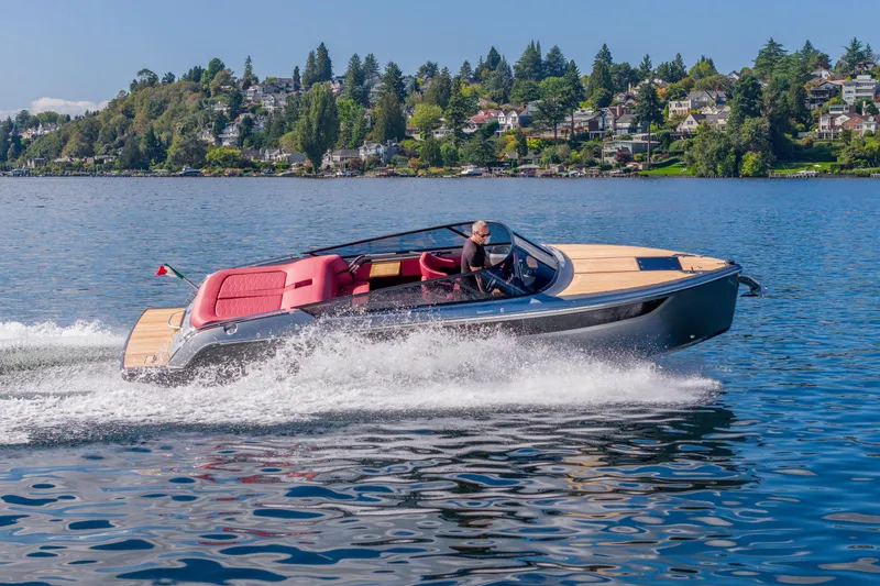 The Image of 2026 Cranchi E26 Classic speedboat cruising on a scenic lake with hillside homes. - 1
