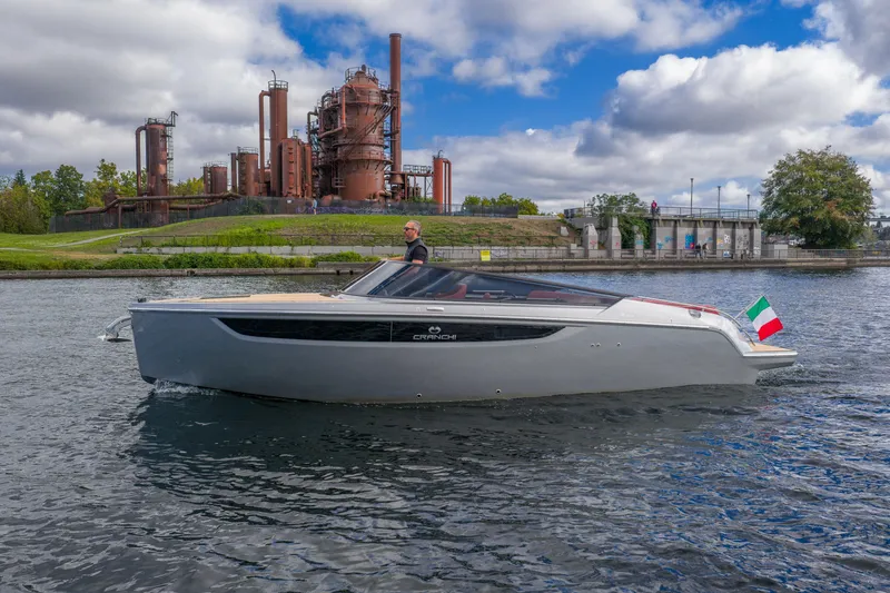 Slide: The Image of 2026 Cranchi E26 Classic boat cruising near industrial backdrop under cloudy sky. - 29