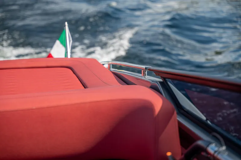 Slide: The Image of 2026 Cranchi E26 Classic boat with red seating and Italian flag on water. - 49