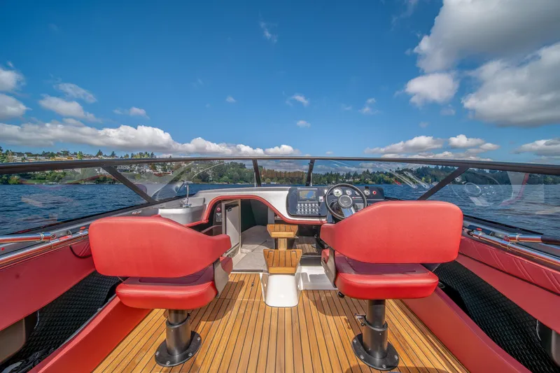Slide: The Image of 2026 Cranchi E26 Classic boat interior with red seats and wooden deck, on a sunny day. - 9