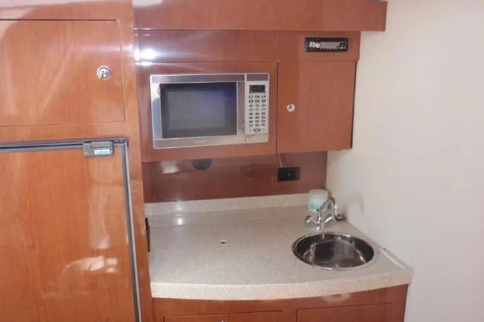 Slide: The Image of 2006 Regal Commodore 3560 IO yacht kitchenette with microwave, sink, and wooden cabinetry. - 11