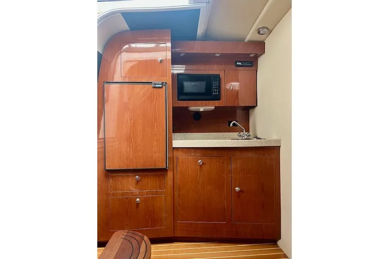 Slide: The Image of 2006 Regal Commodore 3560 IO yacht interior with wooden cabinetry, microwave, and compact kitchen area. - 20