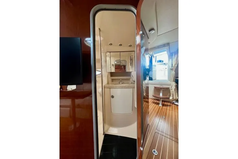 Slide: The Image of Interior of 2006 Regal Commodore 3560 IO yacht, featuring a compact bathroom and wooden flooring. - 23