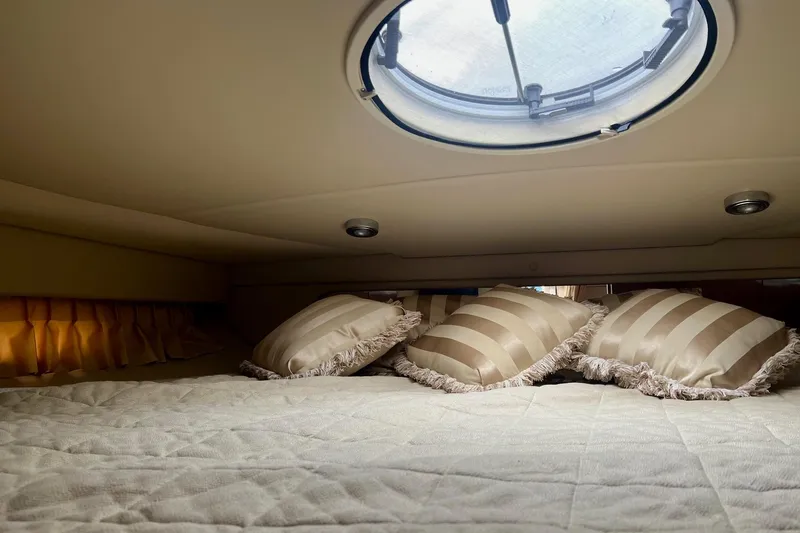 Slide: The Image of Cozy cabin interior of 2006 Regal Commodore 3560 IO with striped pillows and round window. - 24