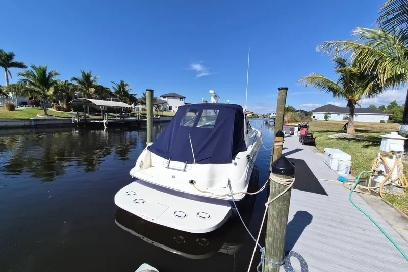 Slide: The Image of 2004 Sea Ray 380 Sundancer docked by palm trees under clear blue sky. - 2