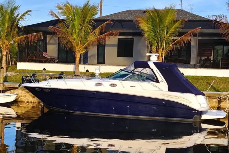 Slide: The Image of 2004 Sea Ray 380 Sundancer yacht docked by a waterfront home with palm trees. - 30