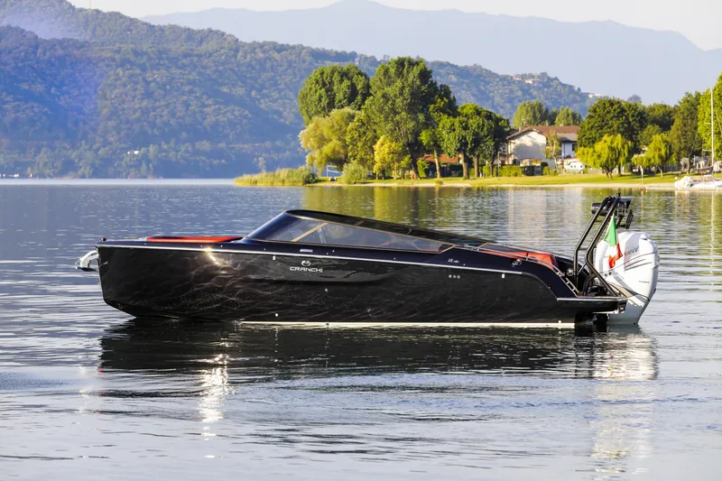 The Image of 2026 Cranchi E26 Rider boat on a serene lake with scenic mountain backdrop. - 1