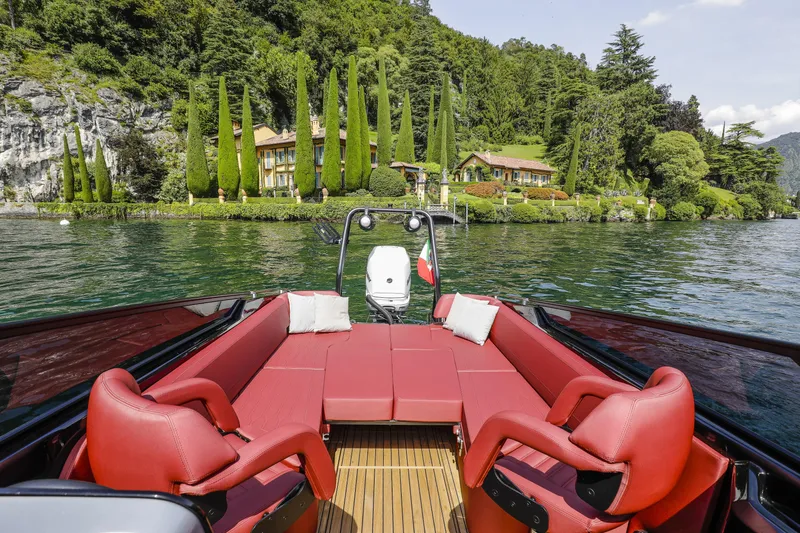 Slide: The Image of Luxurious 2026 Cranchi E26 Rider boat with red seating, scenic lakeside villa view. - 11