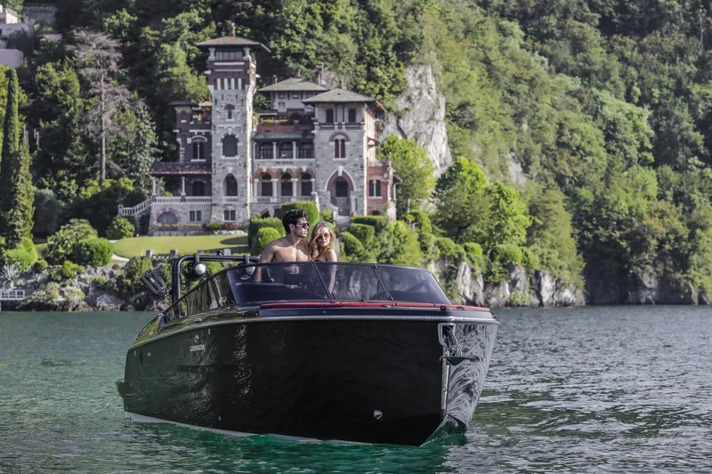 Slide: The Image of 2026 Cranchi E26 Rider boat on scenic lake with historic mansion backdrop. - 13