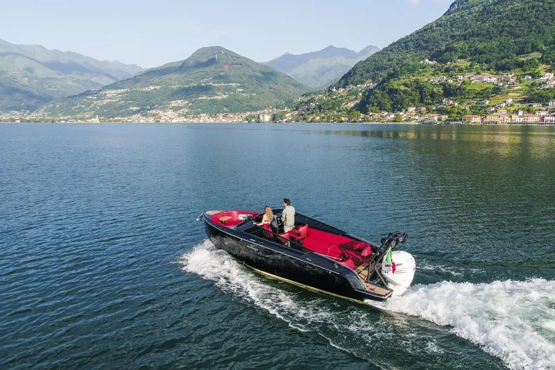 Slide: The Image of 2026 Cranchi E26 Rider boat cruising on a scenic lake with mountainous backdrop. - 14