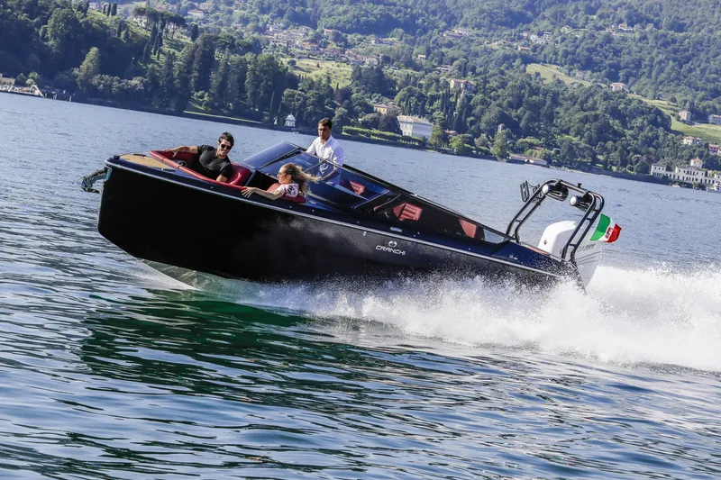 Slide: The Image of 2026 Cranchi E26 Rider speedboat cruising on a scenic lake with passengers. - 18