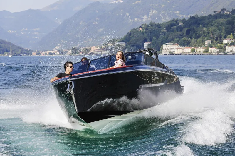 Slide: The Image of 2026 Cranchi E26 Rider cruising on a scenic lake with passengers enjoying the ride. - 23