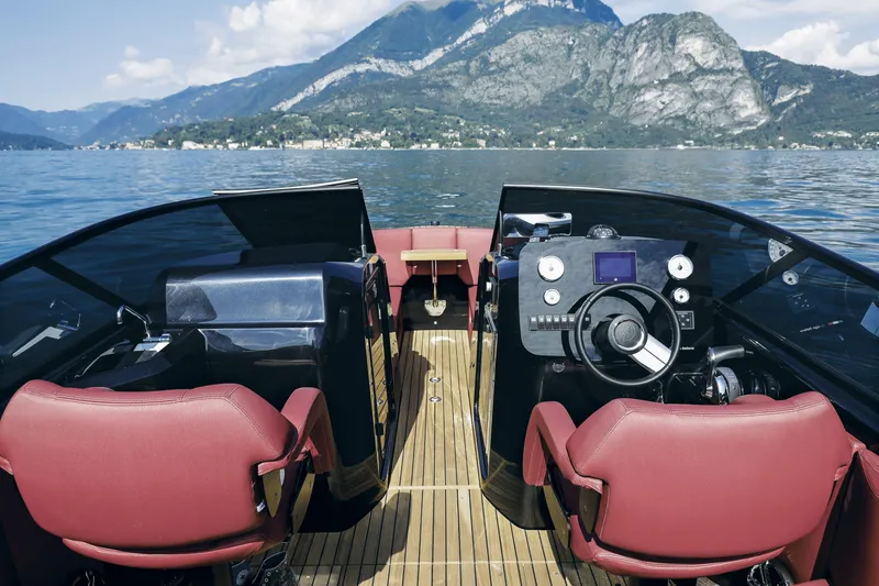 Slide: The Image of 2026 Cranchi E26 Rider boat interior with red seats, steering wheel, and scenic mountain view. - 28
