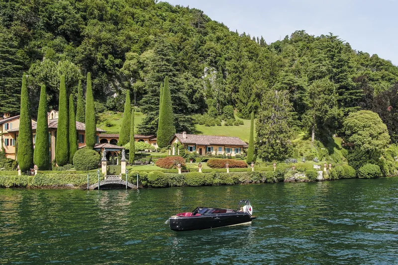 Slide: The Image of Cranchi E26 Rider 2026 boat on scenic lake with lush greenery and elegant villa backdrop. - 34