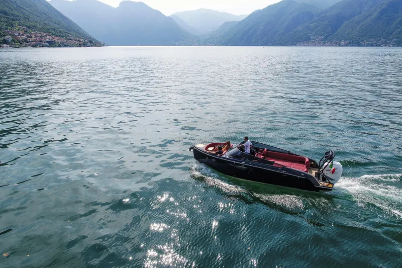Slide: The Image of 2026 Cranchi E26 Rider boat cruising on a scenic lake with mountainous backdrop. - 39